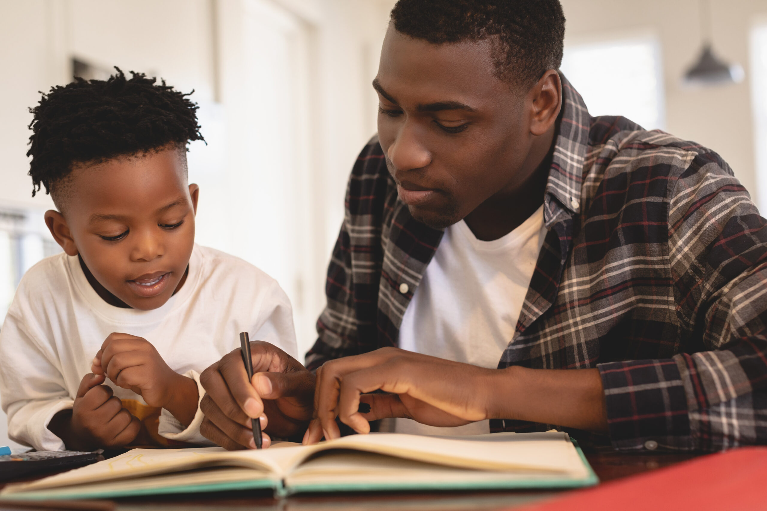Adult helping young boy with homework sitting at table