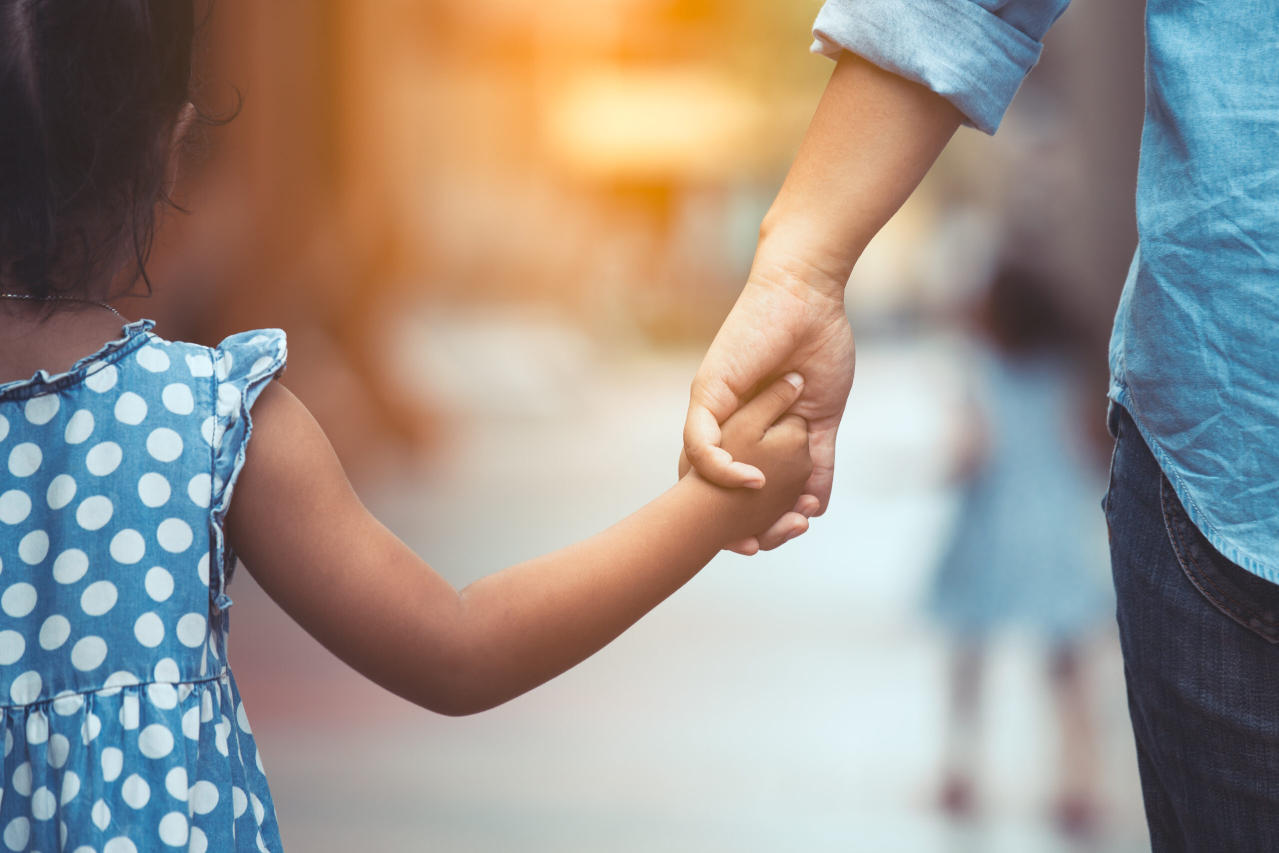 Adult and young girl holding hands