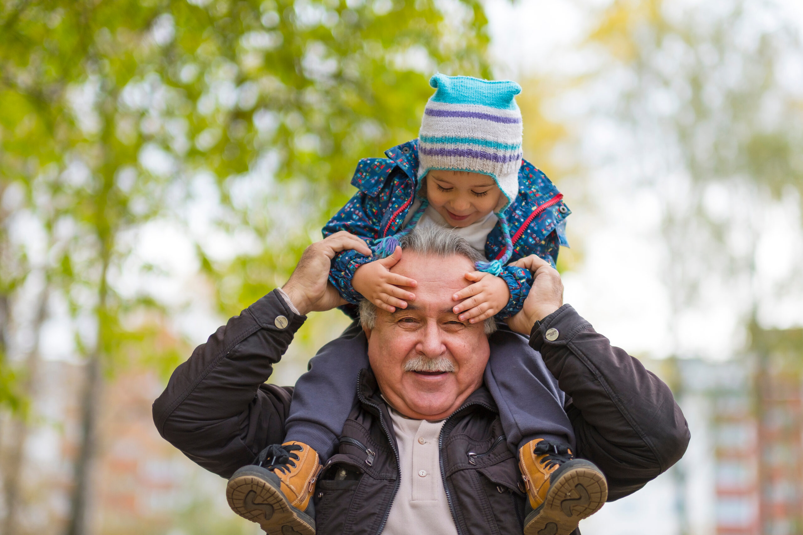 Happy senior man smiling with young boy on shoulders