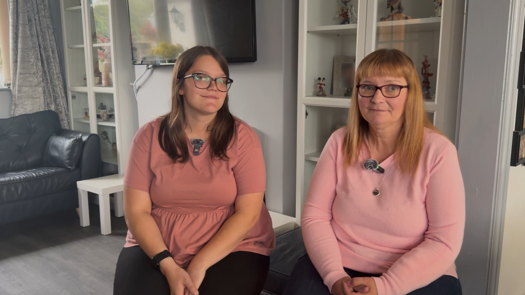 Two ladies wearing pink jumpers and glasses