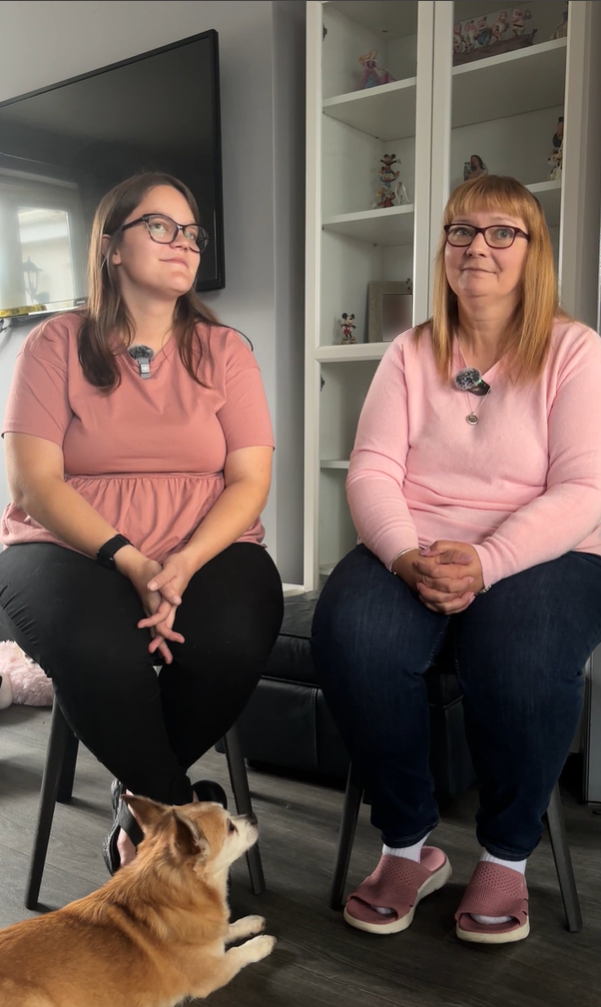 Two ladies wearing pink jumpers and glasses