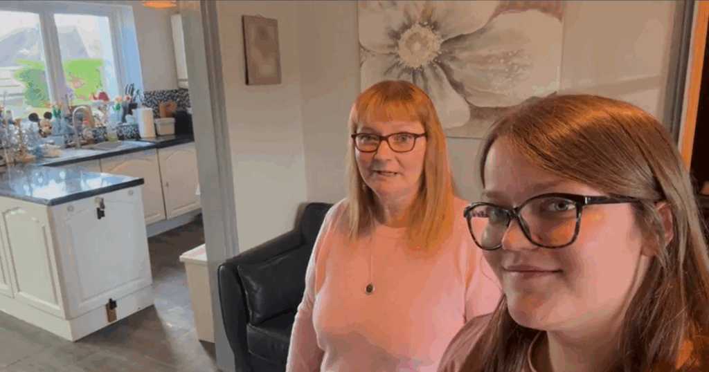 Two ladies wearing pink jumpers and glasses